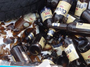 Beer bottles discarded in a dumpster... by the recycling bin.